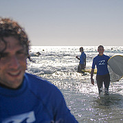 studente di surf durante la lezione in mare allievo del corso di surf cavalca un’onda sotto la guida dell’istruttore