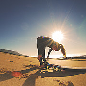esercizi di allungamento prima del surf partecipanti che fanno stretching in spiaggia prima del corso di surf