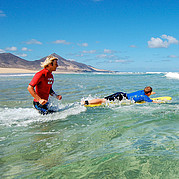 sul punto di entrare in acqua con la tavola surfisti pronti a entrare in mare per una sessione di surf sulle onde di Fuerteventura