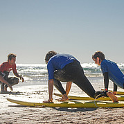 pratica del take off sulla sabbia durante il corso di surf istruttore che spiega la tecnica del take off sulla spiaggia prima di entrare in acqua