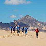jogging leggero al caldo per riscaldarsi surfisti che corrono sulla spiaggia al sole per riscaldamento prima della lezione di surf