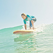 take off su un’onda verde surfista in piedi sulla tavola mentre esegue un take off su un’onda non frangente
